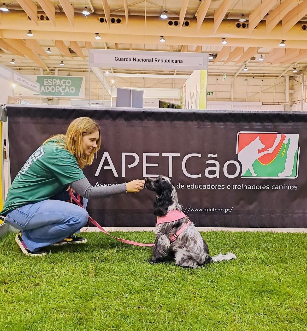 Educadora canina a trabalhar com um cão junto ao painel da APETcão no Pet Festival